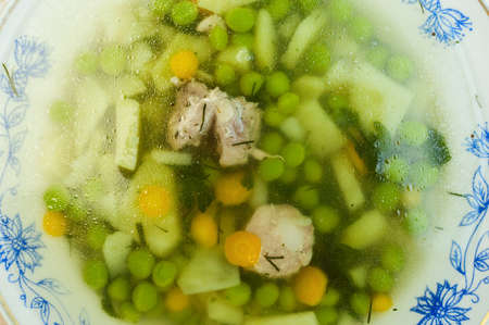 bowl of soup with green vegetables and sausageの写真素材