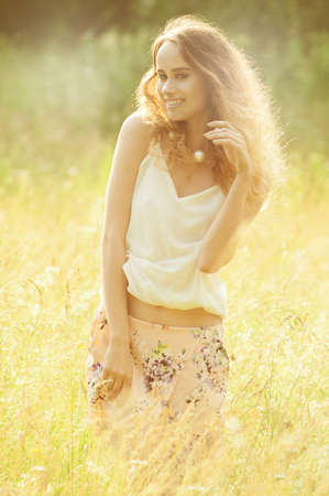 curly  girl in a white blouse on a summer meadowの写真素材