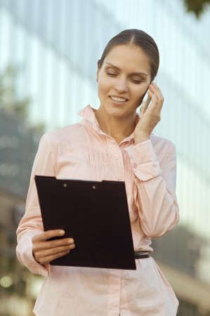 business woman speaks by phone and looks in documentsの写真素材