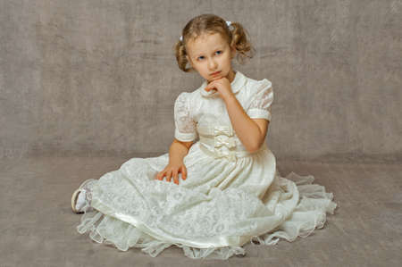 blonde teen girl sitting in a white retro dress, not a gray backgroundの写真素材