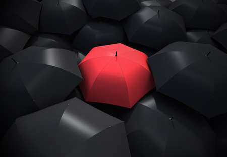 Red umbrella standing out from background of black umbrellasの写真素材
