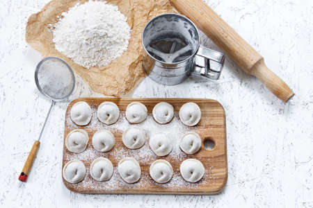 The process of making home-made dumplings. Raw homemade dumplings on a wooden board. Molding dumplings.の写真素材