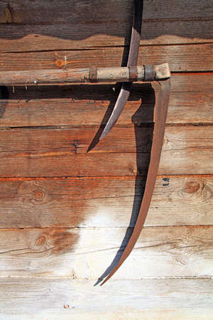 aging scythe on wallの写真素材