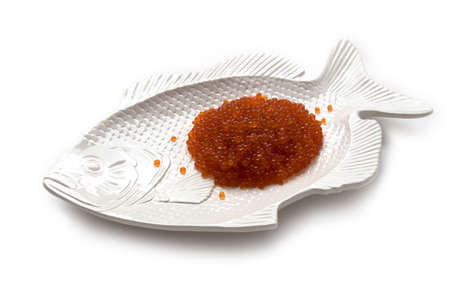 Red salmon caviar on a fish-shaped plate, isolated on whiteの写真素材