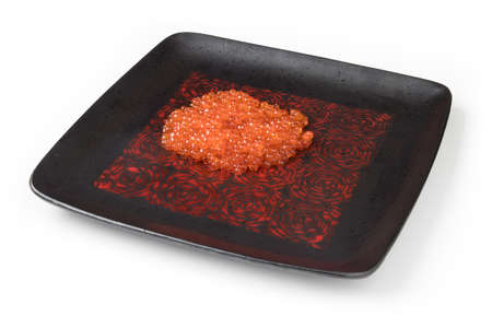 Red salmon caviar on a black square plate, isolated on whiteの写真素材