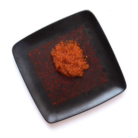 Red salmon caviar on a black square plate, isolated on white, top viewの写真素材