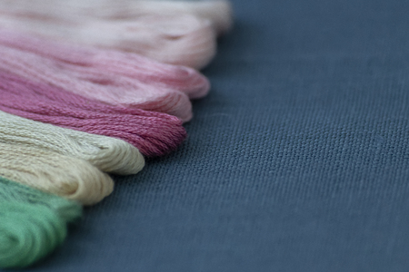 Multi-colored threads for embroidery on blue canvas. Place for text. Macro