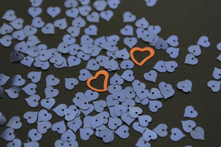 Dark sequins in the shape of a heart on a black background. Two red heartsの写真素材