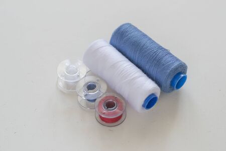 Colored bobbins and spools of thread for machine sewing on a light background close-upの写真素材
