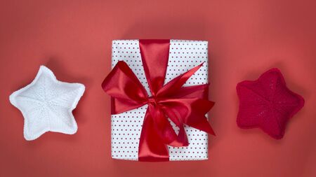 Gift box with red bow and knitted stars close-up. Gift concept for needlewoman.