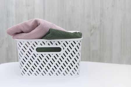White plastic basket with clean multi-colored towels on a wall background. Copy spaseの写真素材