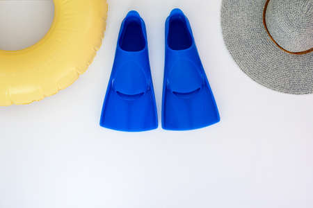 Blue flippers, swimming circle, hat on a white background. Baner Flat lay. Copy space