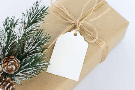 Christmas and New Years background close-up. Gift box wrapped in kraft paper with jute cord. Decorated with a label and a branch with conesの写真素材