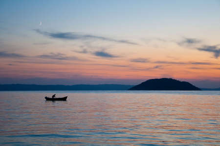 sunset, fisherman with nets on his boatの写真素材