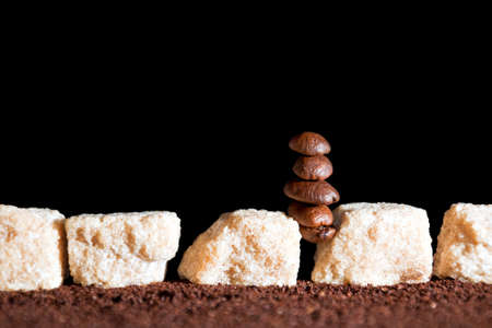 stack of coffee beans  and cane sugar cubes  on a black background の写真素材