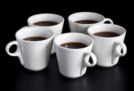 five white coffee cups isolated on a black backgroundの写真素材