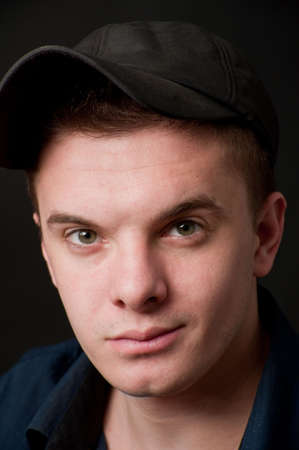 portrait  young green-eyed man in  cap on a black backgroundの写真素材