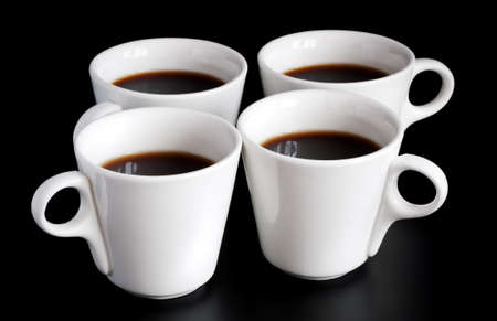 four white coffee cups isolated on a black backgroundの写真素材