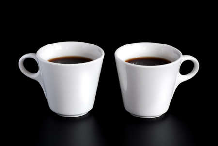 two white coffee cups  isolated on a black backgroundの写真素材