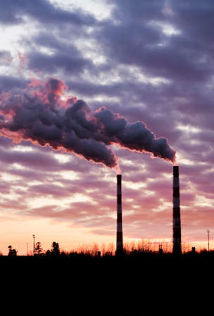 Pollution spewing into the air from industrial chimneys, at sunset.の写真素材