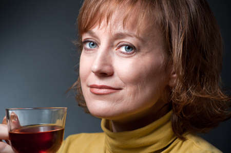 portrait of a blue-eyed woman in a pale green sweater with a cup  tea