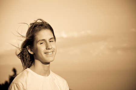 monochrome portrait of a teenager with flying long hair, against the skyの写真素材
