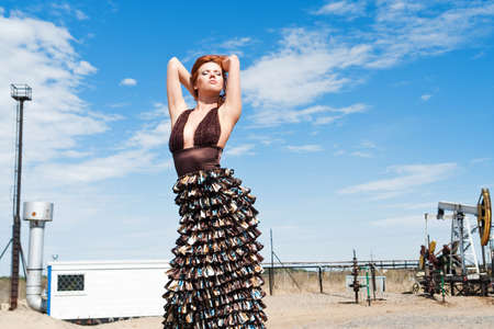 Pretty young redhead woman with arms raised  against the industrial landscapeの写真素材