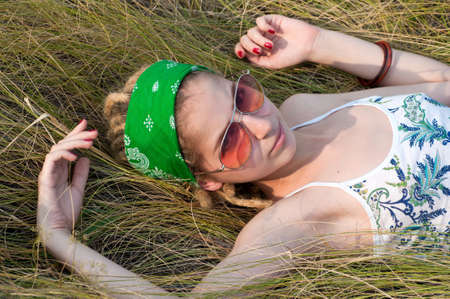 young woman  in a green  headscarf and sunglasses lying on the grassの写真素材