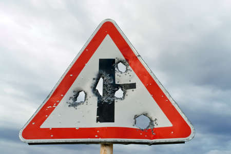 shot-riddled road sign against cloudy skyの写真素材