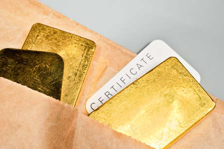 Processing and global trading of precious metals. Gold bars, certificate and paper pack. Closeup.の写真素材
