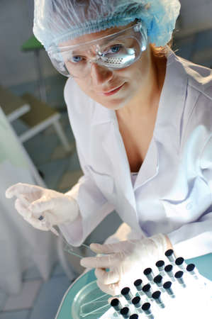 Female doctor in glasses examines a sample. 
Could be useful for medicine, hospital, research and development, clinical studies, forensics, science etcの写真素材