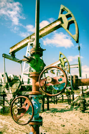Extraction of oil  Wellhead with valve armature and pump jack  Toned の写真素材