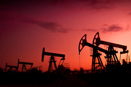 Oil pumps at sunset sky background. Selective focus, shallow depth of field.の写真素材