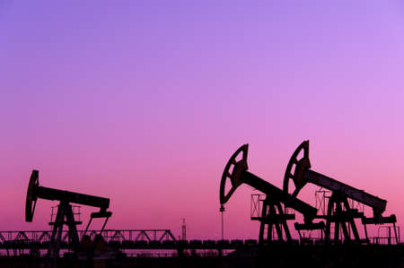 Pump jack group on a sunset sky background. Extraction of oil. Toned.の写真素材