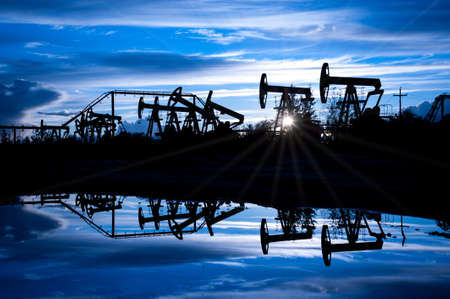 Oil pump jacks group on a sunset sky background. Toned blue.の写真素材