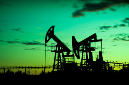 Oil pump jacks at sunset sky background. Selective focus, shallow depth of field.の写真素材