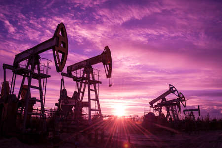 Oil pump jacks at sunset sky background. Toned.の写真素材