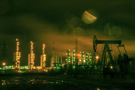 Oil rigs and brightly lit industrial site at night. Toned.の写真素材