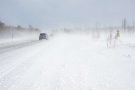 Cars on the winter road in snowstorm time. Risk of snow and ice. Blizzard.の写真素材