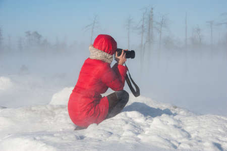 Woman photographer taking pictures during winter blizzard.の写真素材