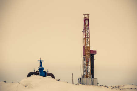 Pump jack and oil rig in the oilfield situated in the beautiful winter forest. Environmental pollution. Oil and gas concept.の写真素材