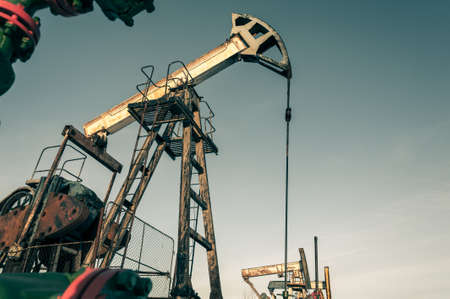 Oil pump jack and wellhead in the oilfield. Oil and gas concept.の写真素材