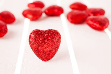 Many glitter red hearts on white wood background.の写真素材