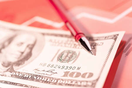 Finance background with money, stock market chart, graph and pen. Living coral toned.の写真素材