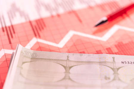 Finance background with money, stock market chart, graph and pen. Living coral toned.の写真素材