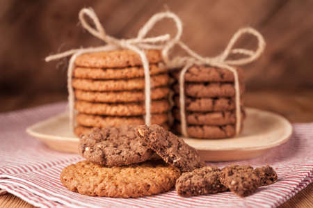 Various shortbread, oat cookies, chocolate chip biscuit on dark rustic wooden table.
