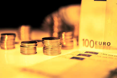 Close up view of stack coins and cash money euros bills. Finance and business concept.