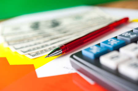 Business and financial background with dollars, data, pen and calculator. Bookkeeping background.の写真素材