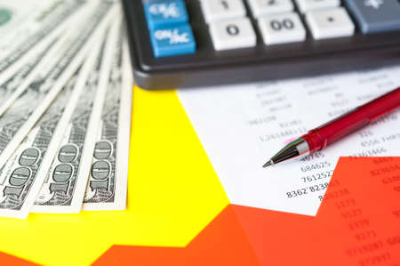 Business and financial background with dollars, data, pen and calculator. Bookkeeping background.