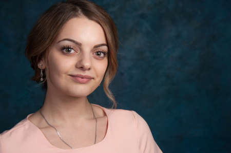 Portrait of a young attractive woman with blond hair on a dark blue background.の写真素材